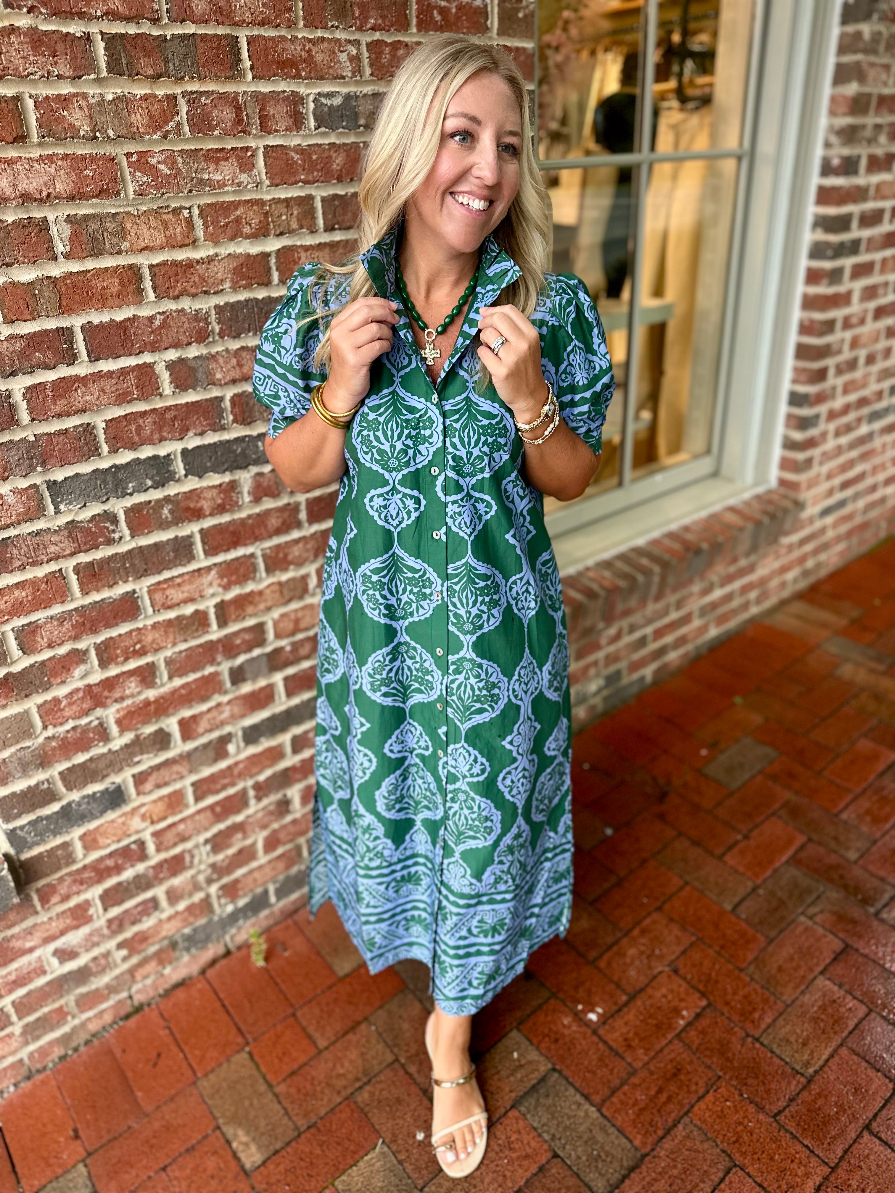 Model wearing a green and blue patterned button-front midi dress with a collared neckline and short sleeves from Pink Chair Boutique.
